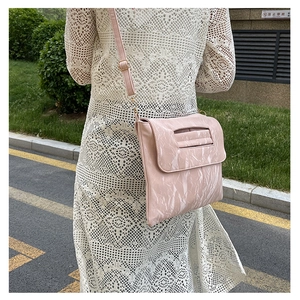 Détail du sac bandoulière rose clair avec texture marbrée et boucle dorée