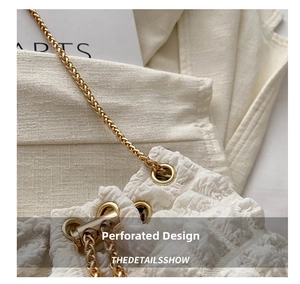 Detail of white bubble texture fabric with golden metal eyelets and matching chain strap