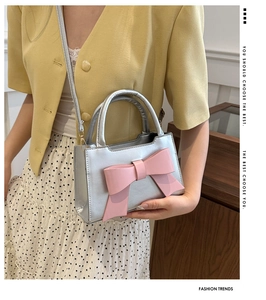Detail of silver metallic handbag featuring a large pink bow and elegant hand-carry style