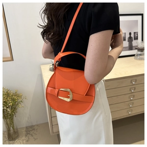 Detail of bright orange semi-circle saddle bag with gold buckle on a modern model