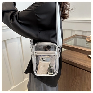Detailed view of transparent PVC crossbody bag showing dual zipper and wide fabric strap
