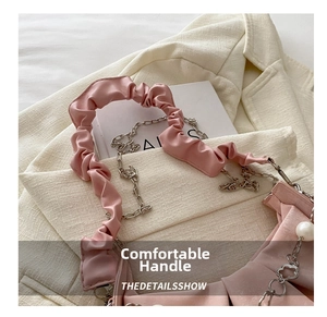 Detail of pink pleated leather handbag with white pearls and flower pendant chain