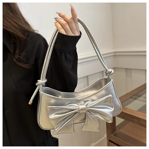 Detail of metallic silver shoulder bag featuring a large bow and premium leather texture
