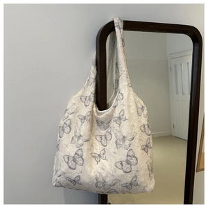 Detail of floral tote bag with blue butterfly embroidery and textured fabric finish