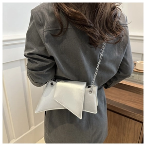 Chic silver asymmetric geometric chain bag worn over a dark grey blazer for women