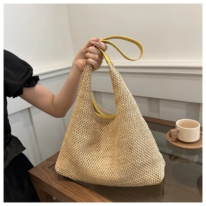 Detail of handwoven straw tote bag with vibrant yellow leather handle and trim