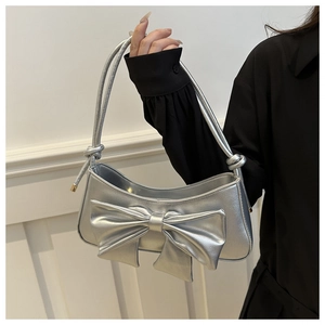 Detail of silver metallic handbag featuring large bow design and knotted shoulder strap