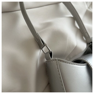 Detail of silver gray shoulder bag showing precise stitching and metallic ring buckle