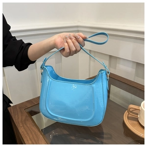 Detail of light blue glossy patent leather shoulder bag with smooth mirror finish texture