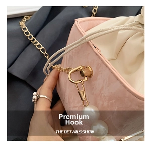 Détail du sac seau en cuir rose texturé avec chaîne dorée et anse en grosses perles