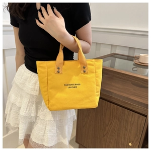 Detail of bright yellow tote bag with black fashion print and durable canvas texture