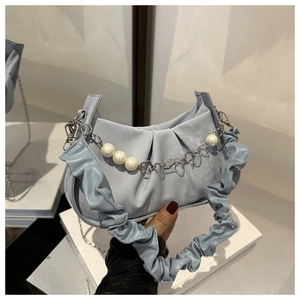 Close-up of light blue pleated cloud bag with elegant pearl and metal chain detail
