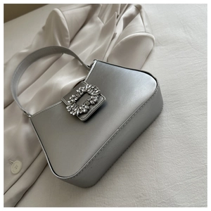 Detailed view of silver satin shoulder bag with a luxury rhinestone buckle on fabric