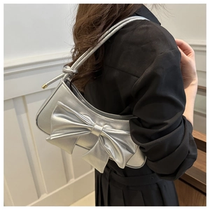 Detailed close-up of a silver bow-knot underarm bag featuring metallic lychee pattern texture