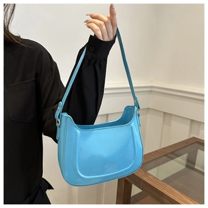 Close-up of light blue glossy leather shoulder bag with smooth patent finish and U-shape