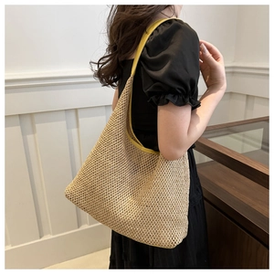 Detail of hand-woven straw shoulder bag with vibrant yellow leather trim and handle