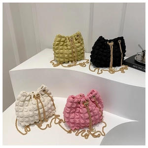 Detailed view of bubble texture bucket bags with gold chains and pearl accents