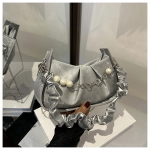 Close-up of silver satin pleated hobo bag with decorative pearl and floral metal chain
