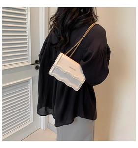 Detail of white wave-edge flap crossbody bag featuring gold chain and brand logo print