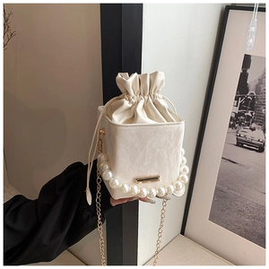 Detail of cream white bucket bag with marble texture, pearl handle and gold chain strap