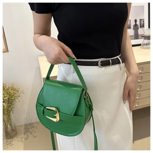 Detail of green leather saddle bag with gold metal buckle and matching shoulder strap