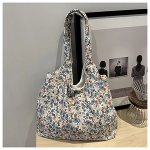 Detailed view of floral canvas tote bag with wide strap hanging in a minimalist room