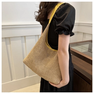 Macro detail of natural straw weaving with vibrant yellow leather trim on a hobo shoulder bag
