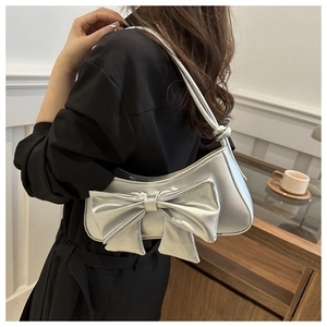 Close-up of a silver bow shoulder bag featuring a metallic PU texture on a female model