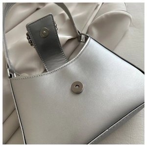 Close-up of the silver underarm bag featuring a metallic finish and magnetic snap closure