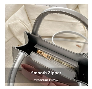 Detailed close-up of smooth gold metal zipper on a silver leather fashion handbag