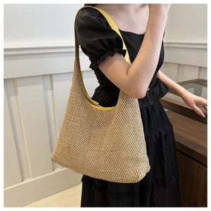 Detail of handwoven texture and bright yellow leather strap on casual straw hobo shoulder bag