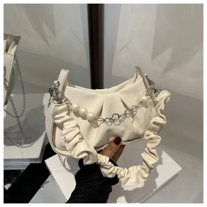 Detail of beaded pearl chain handle on a pleated cream faux leather handbag