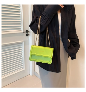Detail of neon green crossbody bag featuring wavy edges and a gold chain strap