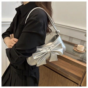 Detail view of the metallic silver bow accent and smooth leather on a shoulder bag