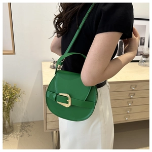 Close-up of bright green saddle bag with gold metal buckle and leather strap