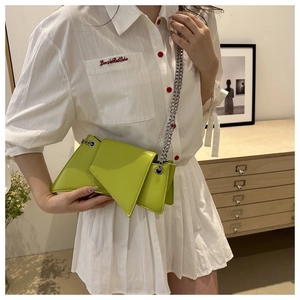 Détail d'un sac géométrique vert citron avec chaîne argentée porté par un mannequin