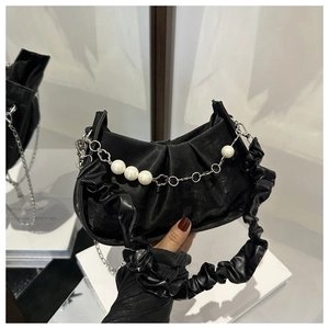 Detail of black pleated handbag with ornate pearl and floral metal chain embellishment