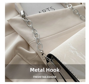 Detail of silver metal chain and hardware swivel hook on white leather crossbody bag
