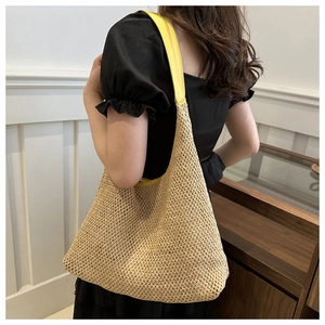 Detail of straw tote bag featuring contrast yellow leather strap on model's shoulder
