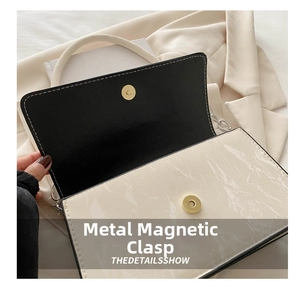 Detail of cream quilted bag featuring a golden magnetic snap and marble texture