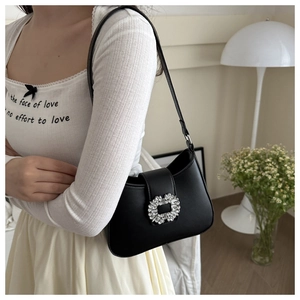Detail of a chic black leather underarm bag featuring a luxury sparkling crystal buckle