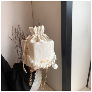 Detail of white marble textured box bag with pearl handle and golden chain strap