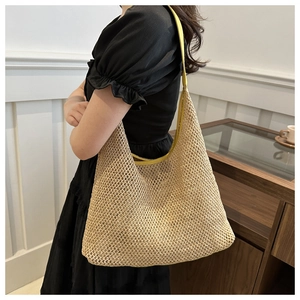 Detail of hand-woven straw tote with vibrant yellow leather trim and handle on shoulder