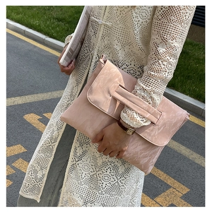Detailed texture of a soft pink pleated PU leather crossbody bag held by a model