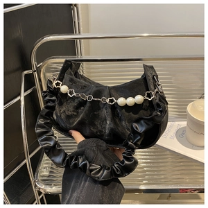 Detail of black pleated cloud bag with elegant large pearl chain and silver flower charms