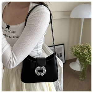 Detail of elegant black PU shoulder bag featuring a crystal buckle in a minimalist setting