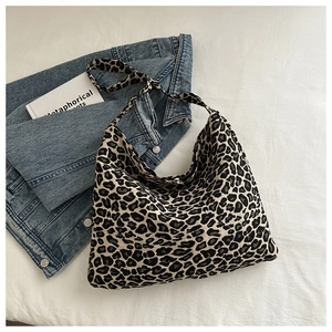 Close-up of leopard print nylon tote bag styled with denim jacket on white fabric
