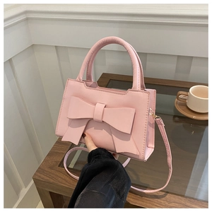 Detailed view of pink tote bag with large decorative bow and elegant top handle
