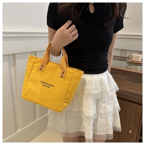 Sac seau en toile jaune vif avec imprimé noir et rivets vu sous un angle de 45 degrés
