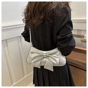 Chic silver bow shoulder bag shown on model for size and metallic texture detail
